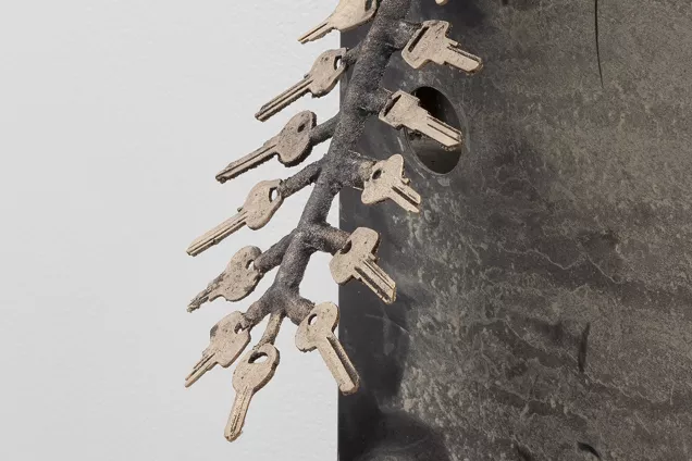 Nycklar som sitter fast på metallstång så de pekar ut som en fjäder. Foto. 